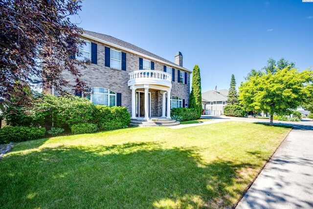 1105 SW Meyer Dr, Pullman, WA 99163 - colonial house with a front yard, a balcony, a chimney, and brick siding
