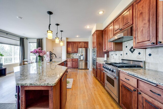 1105 SW Meyer Dr, Pullman, WA 99163 - kitchen featuring appliances with stainless steel finishes, open shelves, light wood-style floors, under cabinet range hood, and brown cabinetry