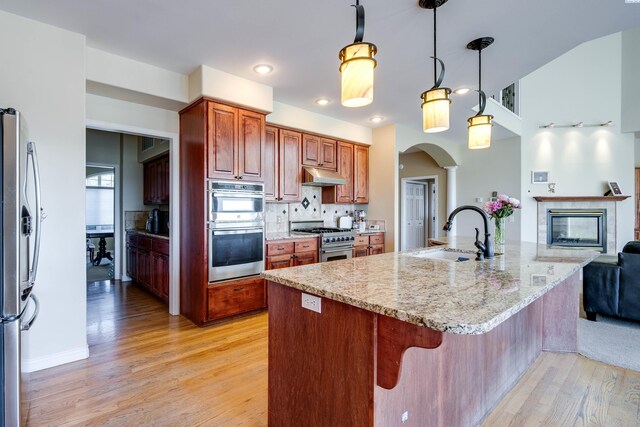 1105 SW Meyer Dr, Pullman, WA 99163 - kitchen featuring appliances with stainless steel finishes, under cabinet range hood, light wood-style flooring, arched walkways, and backsplash