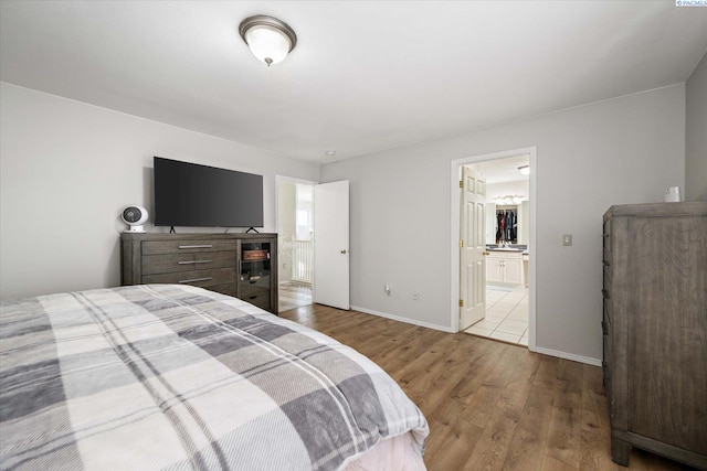 bedroom featuring wood finished floors, connected bathroom, and baseboards