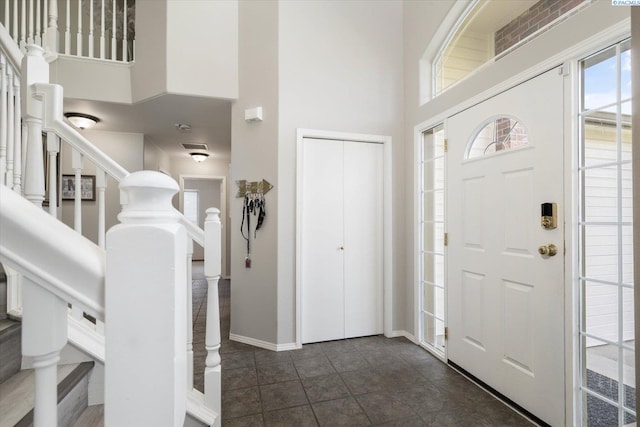 entrance foyer featuring a towering ceiling, stairs, and baseboards