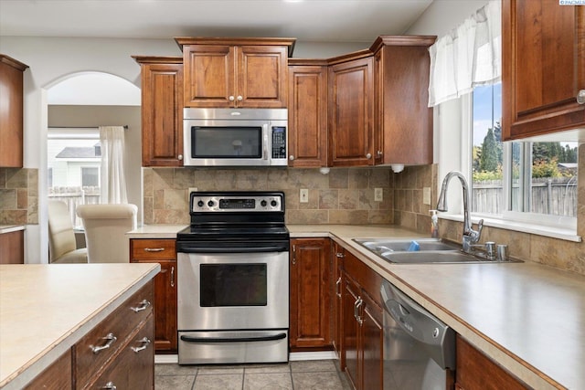 kitchen featuring tasteful backsplash, appliances with stainless steel finishes, light countertops, and a sink