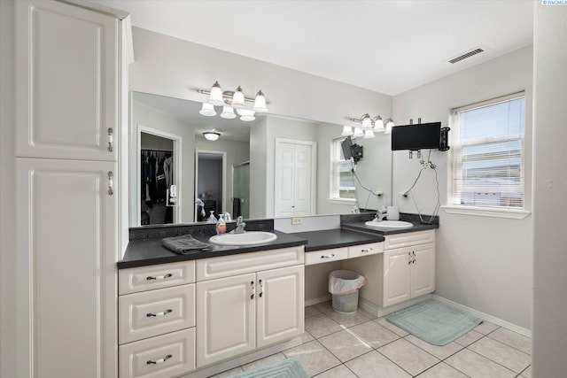 bathroom with a sink, double vanity, visible vents, baseboards, and tile patterned floors