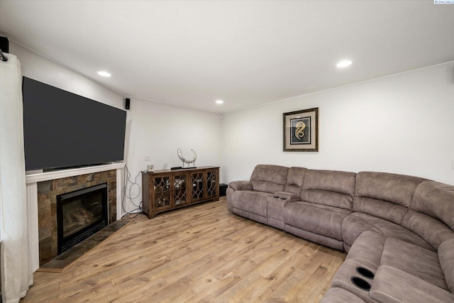 living room with light wood-type flooring, recessed lighting, and a stone fireplace