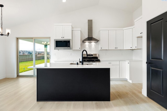 kitchen featuring white cabinets, wall chimney range hood, stainless steel appliances, and light countertops