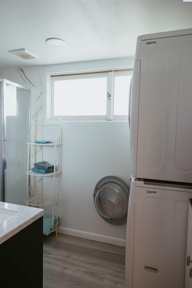 bathroom with hardwood / wood-style flooring, stacked washer / drying machine, and vanity