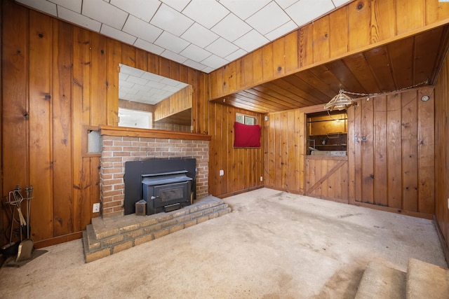 2018 W 2nd Ave, Kennewick, WA 99301 - unfurnished living room featuring a wood stove, carpet flooring, and wooden walls