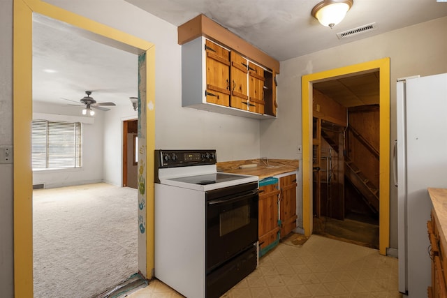 2018 W 2nd Ave, Kennewick, WA 99301 - kitchen with range with electric cooktop, freestanding refrigerator, brown cabinets, a ceiling fan, and light countertops
