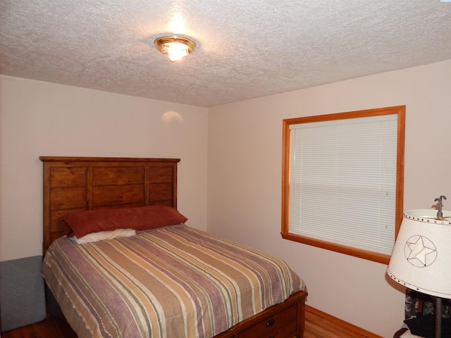 bedroom with a textured ceiling and wood finished floors