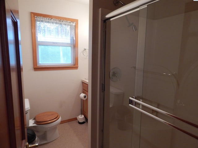 bathroom with toilet, a shower stall, vanity, and baseboards