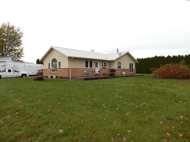 back of property featuring a lawn, a patio area, and brick siding