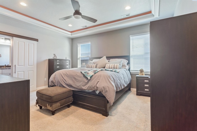 bedroom featuring light carpet, visible vents, and a tray ceiling