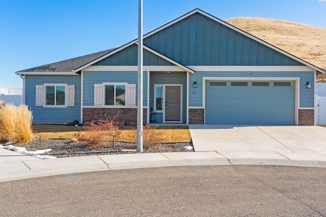 view of front of property featuring board and batten siding, a garage, stone siding, and driveway