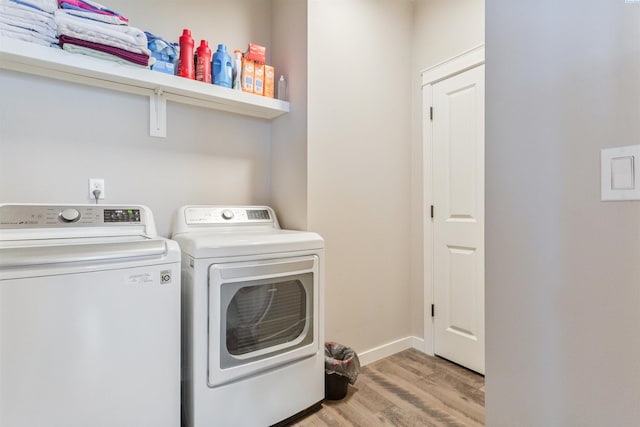 laundry room with washer and dryer, baseboards, wood finished floors, and laundry area