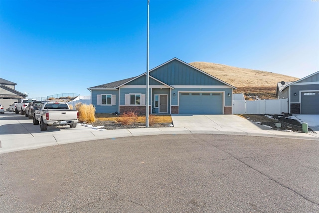 craftsman-style home featuring an attached garage, fence, brick siding, and driveway