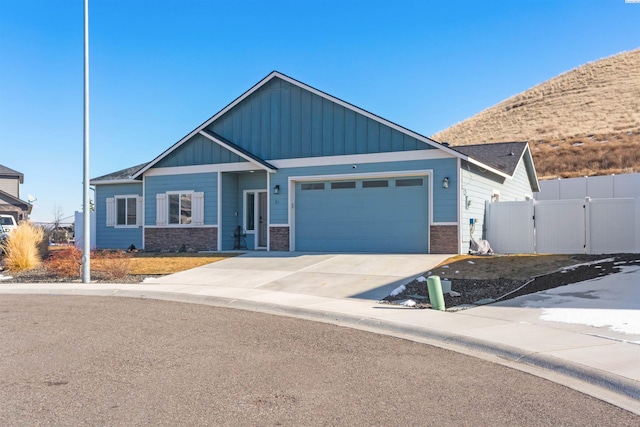 view of front of property featuring a gate, fence, an attached garage, concrete driveway, and stone siding