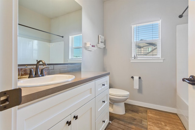 bathroom featuring toilet, wood finished floors,  shower combination, baseboards, and vanity