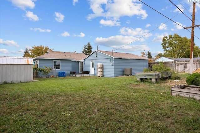 back of property with central AC, a yard, and a shed