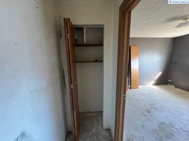 corridor with a textured ceiling and concrete floors