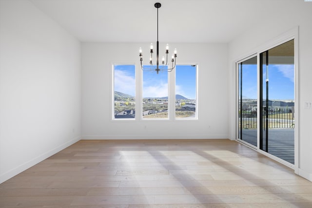 unfurnished dining area featuring an inviting chandelier and light hardwood / wood-style floors