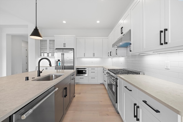 kitchen featuring white cabinetry, appliances with stainless steel finishes, decorative light fixtures, and sink