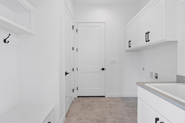 laundry area featuring sink, hookup for a washing machine, cabinets, and light tile patterned flooring