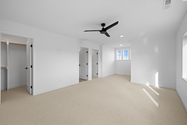 unfurnished bedroom with a spacious closet, light carpet, and ceiling fan