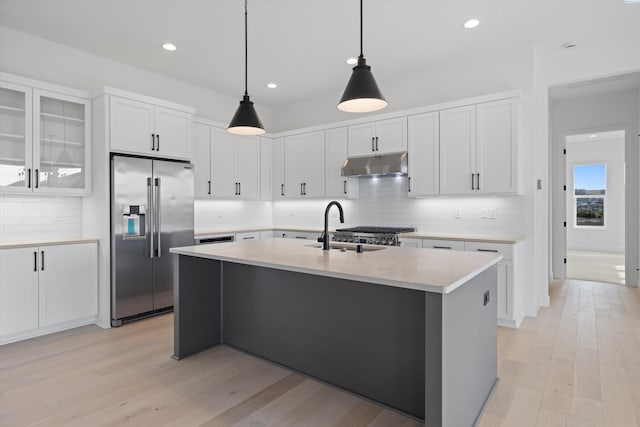 kitchen with white cabinets, an island with sink, sink, and stainless steel fridge