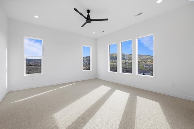 spare room featuring light carpet, a wealth of natural light, and ceiling fan