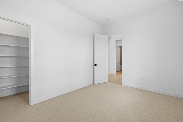 unfurnished bedroom with light carpet, a spacious closet, and a closet