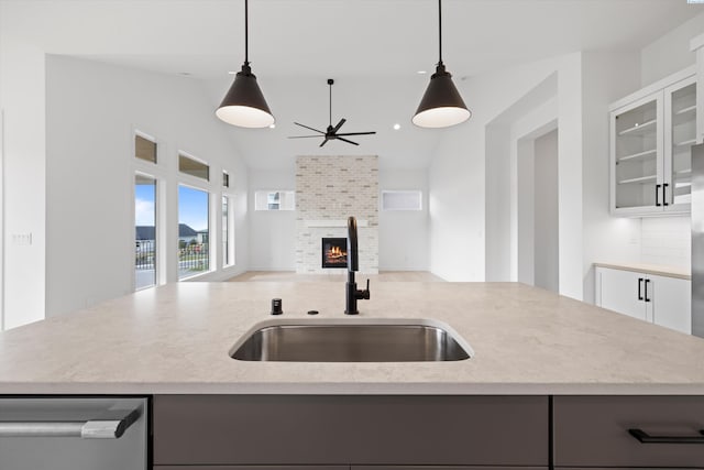 kitchen with sink, white cabinets, hanging light fixtures, a kitchen island with sink, and stainless steel dishwasher