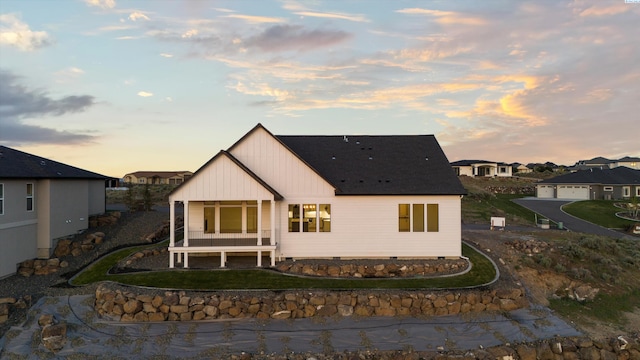 back house at dusk featuring covered porch