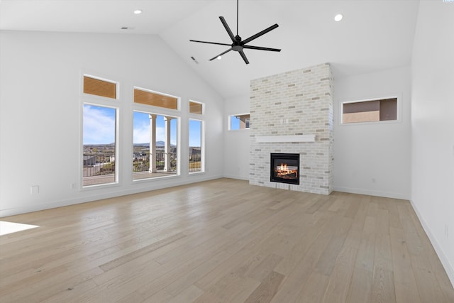 unfurnished living room featuring a brick fireplace, high vaulted ceiling, light hardwood / wood-style floors, and ceiling fan