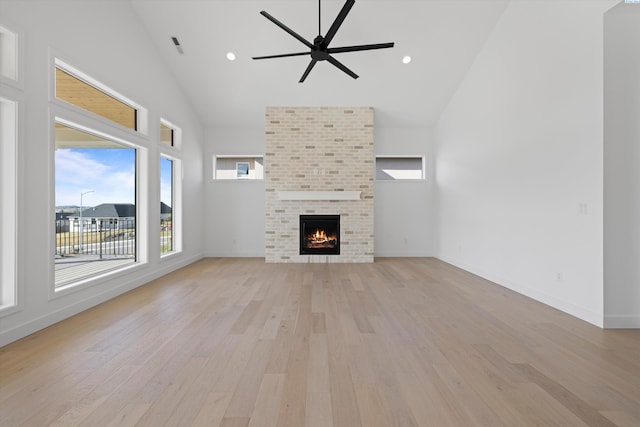 unfurnished living room with ceiling fan, a fireplace, high vaulted ceiling, and light hardwood / wood-style flooring