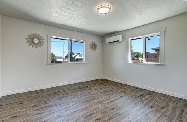 spare room featuring dark hardwood / wood-style flooring, a wall mounted AC, and a textured ceiling