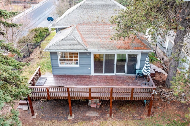 back of house with a wooden deck, fence, and roof with shingles