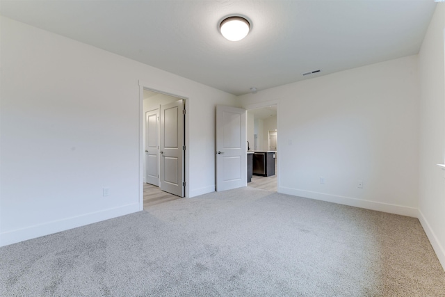unfurnished bedroom with light colored carpet and baseboards