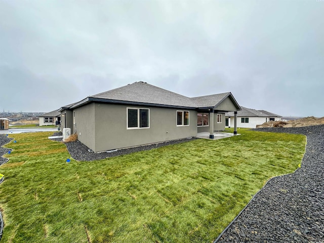back of property with stucco siding, a yard, a patio, and a shingled roof