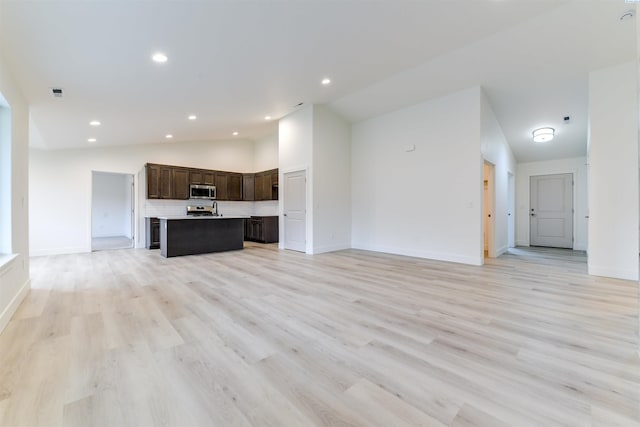 unfurnished living room with vaulted ceiling, light wood-type flooring, baseboards, and recessed lighting