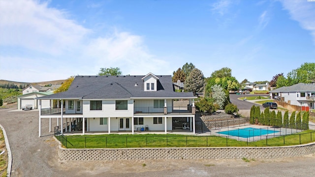 rear view of house featuring a balcony, a patio, a fenced in pool, and a lawn