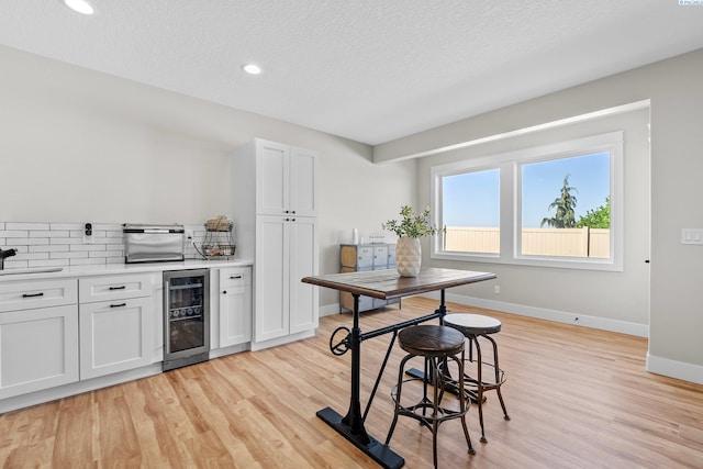 1430 Purple Sage St, Richland, WA 99352 - kitchen featuring beverage cooler, light wood-style floors, a textured ceiling, baseboards, and light countertops