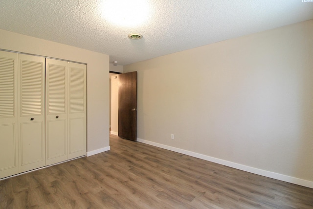 unfurnished bedroom featuring dark wood-type flooring, a closet, and a textured ceiling