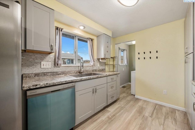 kitchen with gray cabinets, tasteful backsplash, dishwasher, sink, and light hardwood / wood-style floors