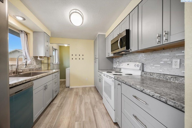 kitchen featuring white electric range oven, sink, gray cabinetry, dishwasher, and light hardwood / wood-style floors