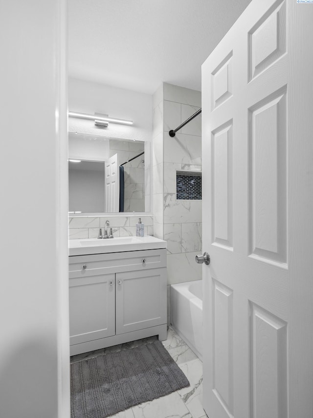 bathroom featuring tiled shower / bath combo and vanity