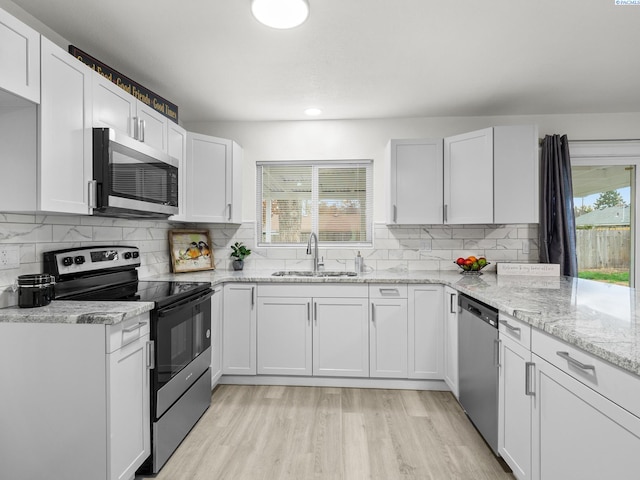 kitchen featuring white cabinetry, appliances with stainless steel finishes, light hardwood / wood-style floors, and sink