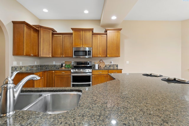 kitchen featuring sink, stainless steel appliances, and dark stone counters