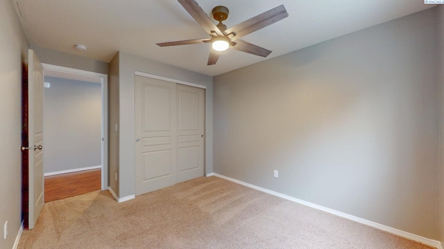 unfurnished bedroom featuring light carpet, a closet, and ceiling fan