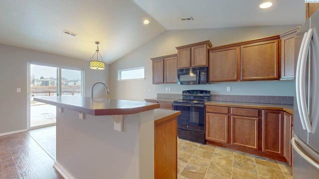 kitchen featuring a center island with sink, lofted ceiling, black appliances, a breakfast bar area, and pendant lighting