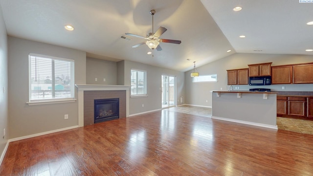 unfurnished living room with ceiling fan, light wood-type flooring, and vaulted ceiling